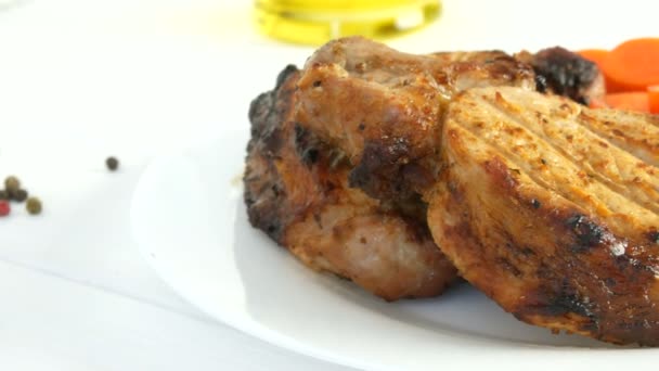 Közelkép a finom lédús friss szeletek grillezett steak entrecote sertéshús mellett cseresznye paradicsom és friss zöldség uborka fehér éttermi tányéron - Felvétel, videó