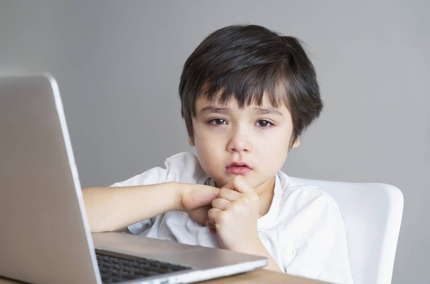 インターネットのログオフ後に泣いているポルトガルの子供、ラップトップ上で漫画を見て悲しい顔を持つ悲しい少年、退屈子供動揺した顔を持つカメラを見て、社会的距離、 -オンライン教育を学ぶ - 写真・画像