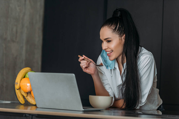 smiling woman holding spoon during video chat on laptop  - Foto, Imagen