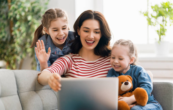 Happy loving family. Young mother and daughters girls using laptop. Funny mom and lovely children are having fun staying at home.    - Foto, afbeelding