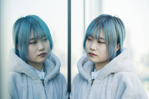 Giovane asiatica (giapponese) donna con i capelli blu e il suo riflesso
 - Foto, immagini