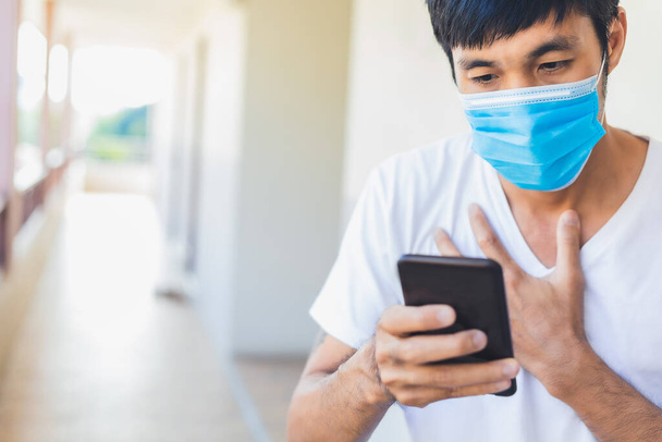 Man Asian φορούν χειρουργική μάσκα κρατήσει smartphone αναζήτηση ειδήσεις covid 19 για να σταματήσει covid 19 ιός covid-19 ή στέμμα προστατεύεται Βοήθεια προστασία Για την κοινωνική αποστασιοποίηση κόσμο και τους ανθρώπους μέθοδο θεραπείας σταματήσει τον ιό - Φωτογραφία, εικόνα