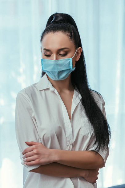 depressed girl in medical mask standing with crossed arms at home - Photo, Image