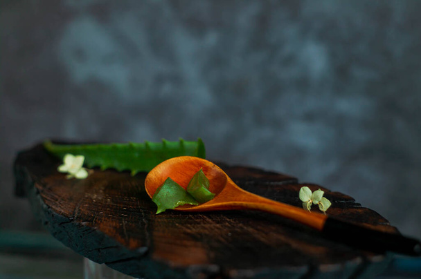 Rebanada de planta de Aloe Vera en una cuchara sobre fondo de madera rústica
 - Foto, imagen