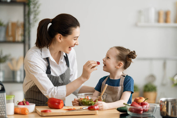 Healthy food at home. Happy family in the kitchen. Mother and child daughter are preparing proper meal. - Φωτογραφία, εικόνα