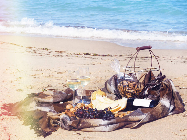 Romanttinen koostumus valkoviiniä, hedelmiä ja pähkinöitä rannalla aurinkoisena päivänä
 - Valokuva, kuva