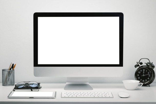 Stilvoller Arbeitsplatz mit leerem Bildschirm-Computerdisplay und Tablet für Attrappen am Schreibtisch mit Tastatur, Maus, Uhr, Brille und Schreibwaren. - Foto, Bild