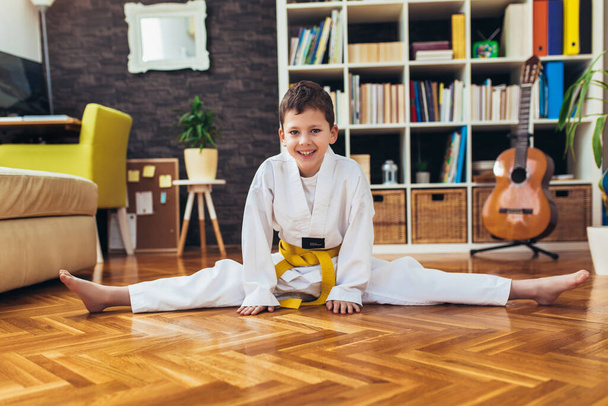 Taekwondo chłopiec ćwiczenia w domu w salonie. - Zdjęcie, obraz
