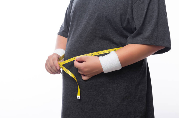 Hombre gordo sosteniendo una cinta métrica para ver su cuerpo aislado sobre fondo blanco. - Foto, Imagen