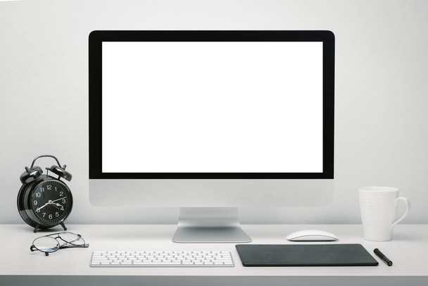 Espace de travail élégant avec écran vierge écran d'ordinateur pour la maquette sur le bureau avec clavier, souris, tasse de café, horloge, lunettes et tablette stylo. - Photo, image