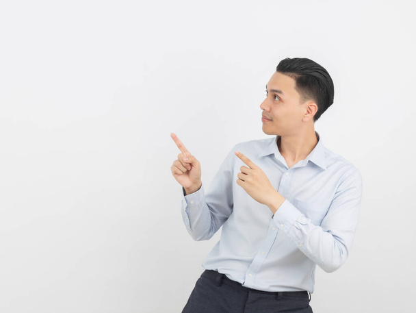 Fiatal ázsiai üzletember kék ingben mutat oldalra egy kézzel, hogy bemutasson egy terméket vagy egy ötlet elszigetelt fehér háttér. - Fotó, kép