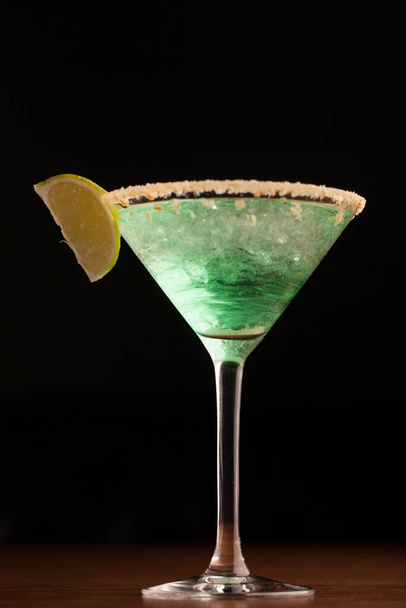 green cocktail in a martini glass rim covered with salt. with a slice of lime. close-up on a black background. macro - Fotó, kép