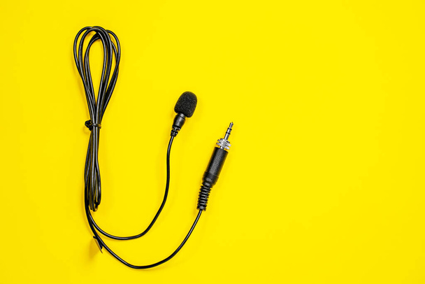 Shotgun microphone buttonhole for audio recorder, with wires, on bright yellow background. Sound record equipment. - Фото, зображення