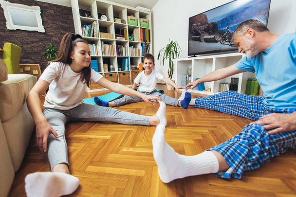 Estiramiento saludable por la mañana - hombre con niños haciendo ejercicio gimnástico en casa - Foto, imagen