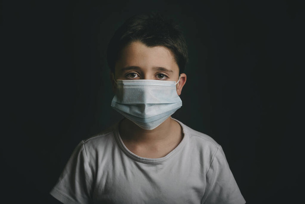 Coronavirus,sad child wearing medical mask over black background - Photo, Image