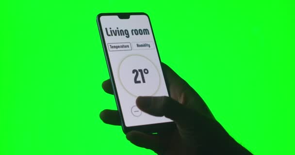 on the green background of the chromakey a man controls the temperature and alarm systems via an app on his mobile phone - Footage, Video