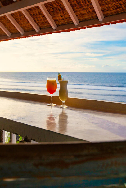 Twee cocktails Pina Colada en Tequila Zonsopgang aan de strandbar met zeezicht bij zonsondergang, Bali, Indonesië - Foto, afbeelding