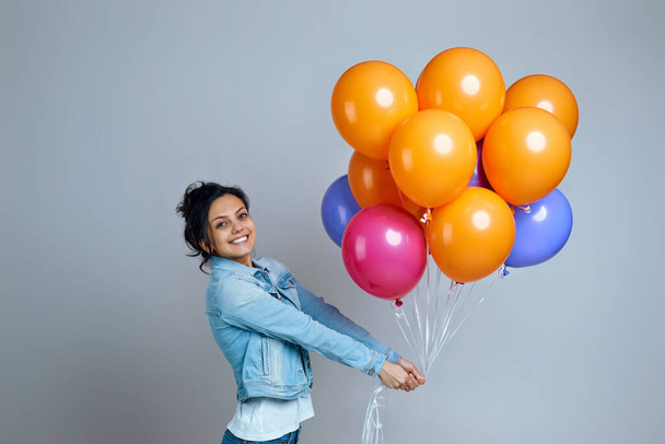 girl in denim posing with bright colorful air balloons - 写真・画像