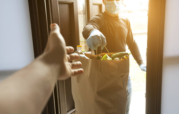 The delivery man gives the bag from grocery store to the woman to her home - Foto, imagen