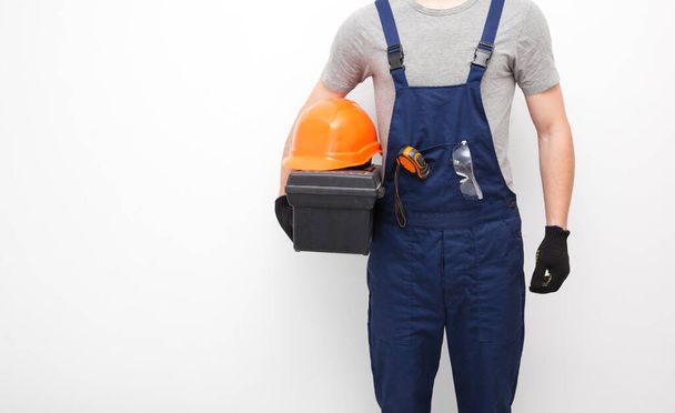 The worker in professional uniform with toolbox in hand on the gray background - Foto, Bild