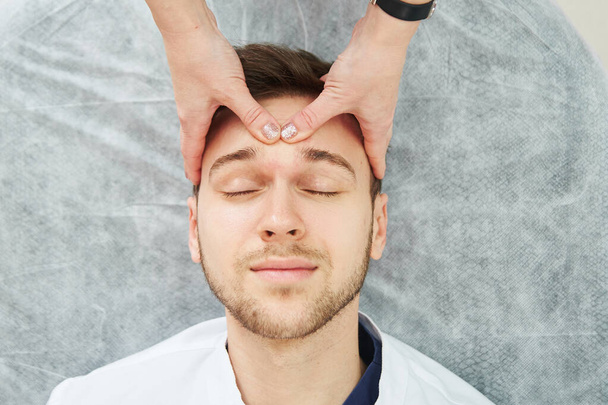 Handsome caucasian man has facial massage in cosmetologist's office close-up. Men's beauty procedures, beautician face skin care - Foto, Imagen
