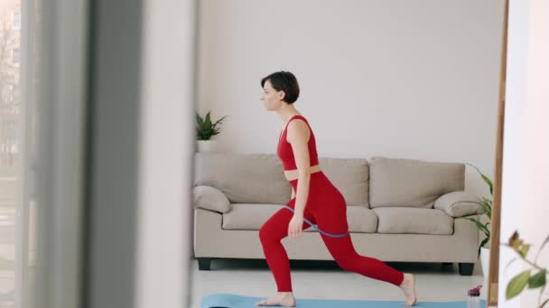 The woman is doing butt exercise with a fitness band - Felvétel, videó