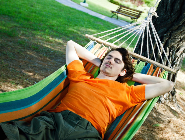 Молодий чоловік відпочиває в гамаку
 - Фото, зображення