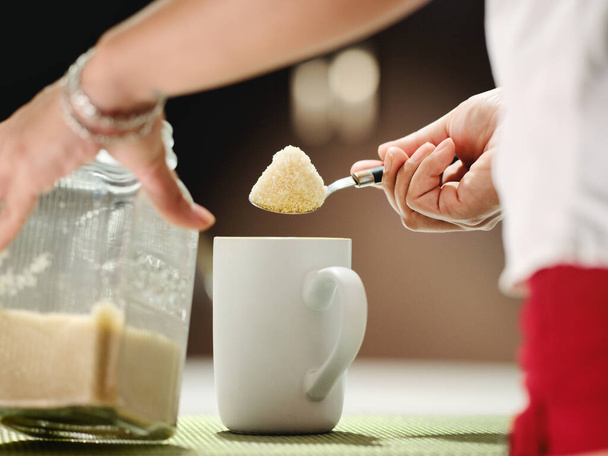 Mujer Añadir un montón de azúcar con cucharadita a taza de café
 - Foto, imagen