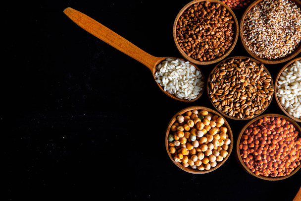 様々なシリアルのボウル。天然穀物や穀物の様々な種類。黒い背景にボウルにさまざまな種類のグラット。健康的な栄養食品 - 写真・画像