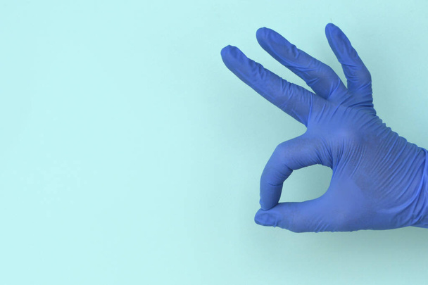 рука в латексних рукавичках добре жест на світло-блакитному фоні
 - Фото, зображення