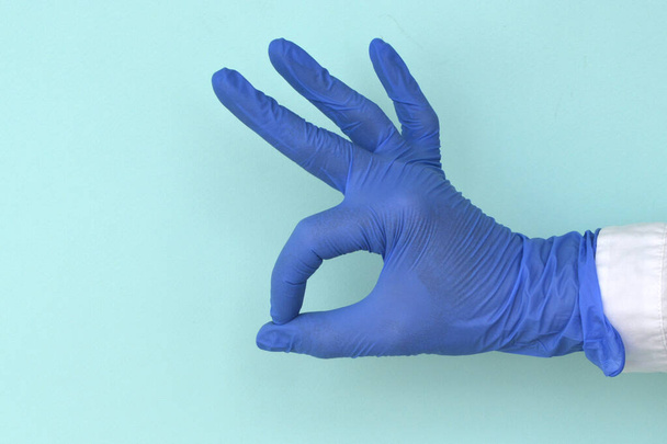 ラテックス手袋の手ライトブルーの背景に大丈夫なジェスチャー - 写真・画像