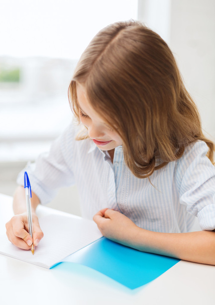 Student girl writing in notebook at school - Photo, Image