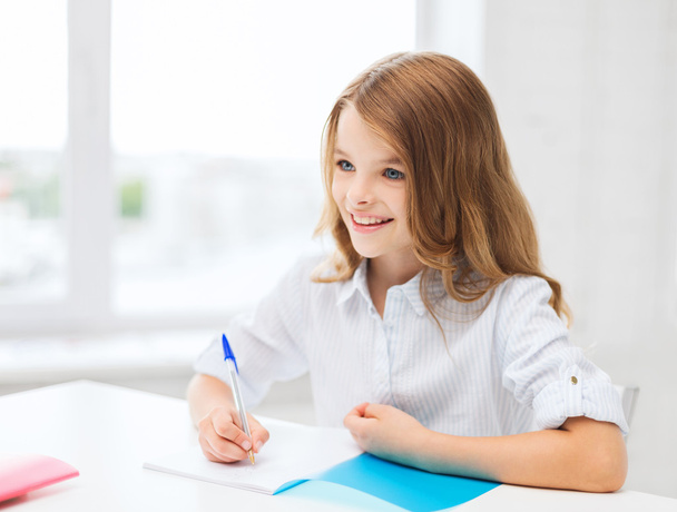 Student girl writing in notebook at school - Foto, imagen