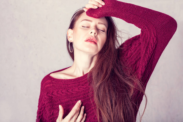 Portrait of a girl who is enjoyment. She in a burgundy knitted sweater  - Zdjęcie, obraz