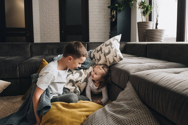 Family in pajamas. Brother and sister. New Year's mood. Fun photo. Play with pillows on the floor. Gray interior. - Φωτογραφία, εικόνα
