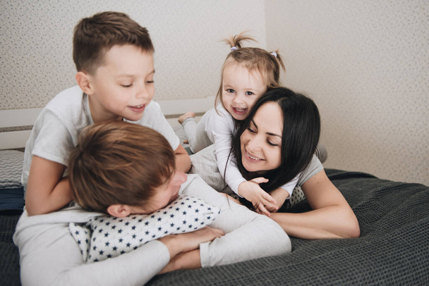 Family at home in pajamas. Daughter and son. Wake up in the morning. Hugging and kissing in the bedroom on the bed. - Zdjęcie, obraz