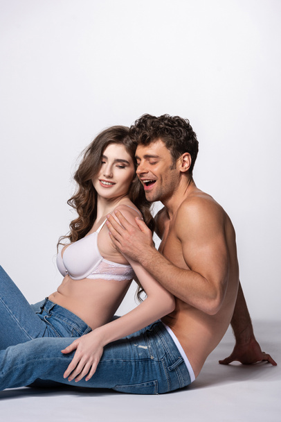 happy and shirtless man touching girl in bra on white  - Foto, afbeelding