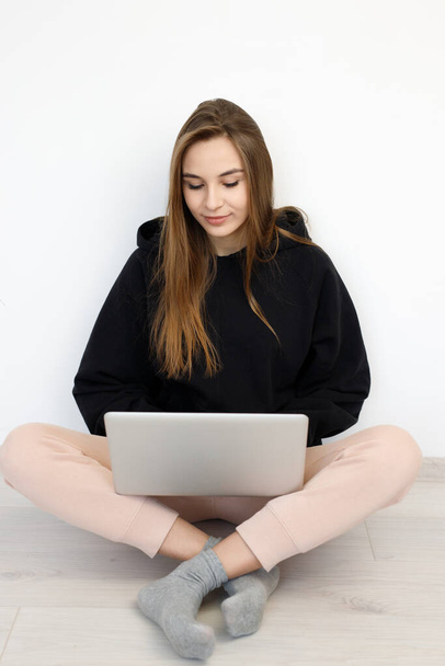 komolyan szabadúszó lány pulóver ül a padlón laptop számítógép, koncepció online oktatás, munka otthonról, fehér háttér, másolás tér - Fotó, kép