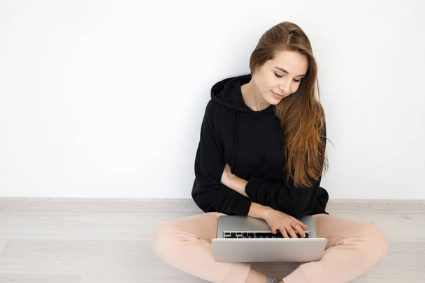 Lachende freelancer meisje vrouw in trui zitten op de vloer met laptop computer, concept online onderwijs, werk van thuis, op witte achtergrond, kopieerruimte - Foto, afbeelding