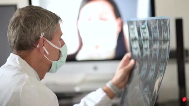 Videoanruf in Coronavirus-Zeiten. Arzt mit Maske und Röntgenuntersuchung zu Hause - Filmmaterial, Video