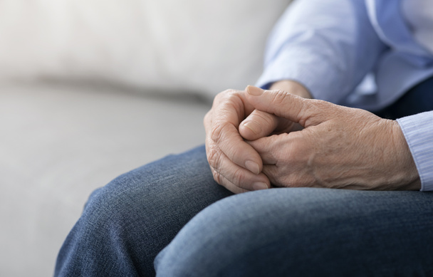 Γήρας και Συνταξιοδότηση. Κοντινό πλάνο των χεριών της ηλικιωμένης γυναίκας που κάθεται στον καναπέ - Φωτογραφία, εικόνα