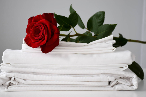 Червона троянда на білій смугастій постільній білизні на білому столі
 - Фото, зображення