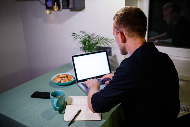 Úspěšný podnikatel, zadní pohled, sedí u stolu doma, dívá se na obrazovku notebooku, cítí radost z vykonané práce, klidný muž pracuje, ruce za hlavou, práce doma - Fotografie, Obrázek