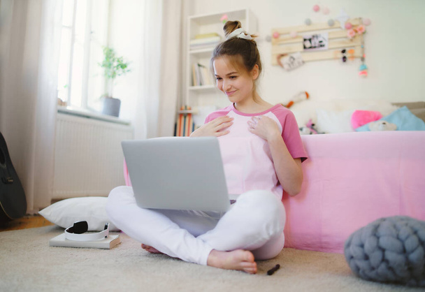Mladá dívka s laptopem sedí na podlaze, relaxační během karantény. - Fotografie, Obrázek