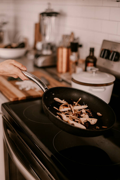 Kookproces in de keuken. Gefrituurde champignons in koekenpan. Kook eten of lunch. Lifestyle keuken. Witte kasten. Bovenkant fornuis. Pro chef-kok in de keuken. Koken trucs. Wilde paddenstoelen. - Foto, afbeelding