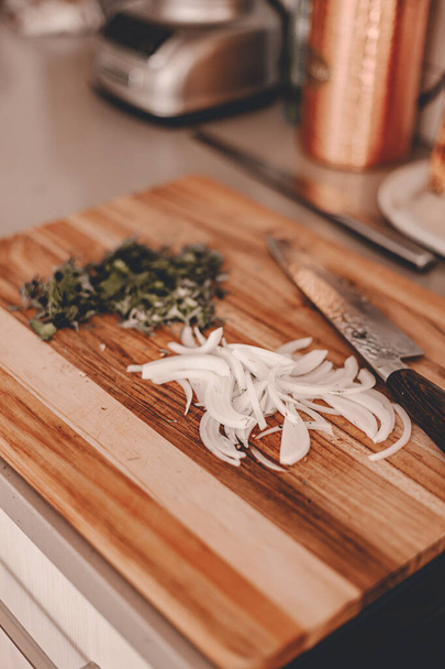 Kesme tahtasında dilimlenmiş sarı soğan ve bitkiler. Şef 'in bıçağı. Profesyonel bir Japon bıçağı. Yaşam tarzı mutfak. Yemek pişirme süreci. Akşam yemeği ya da öğle yemeği için yemek hazırla. Tahta tahta. Pişirmeye hazır. Sotat - Fotoğraf, Görsel