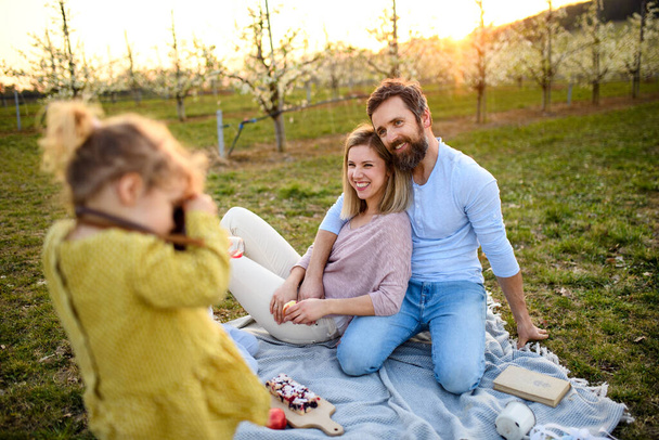 Niña con cámara tomando fotografías en el picnic familiar al aire libre en la naturaleza
. - Foto, imagen