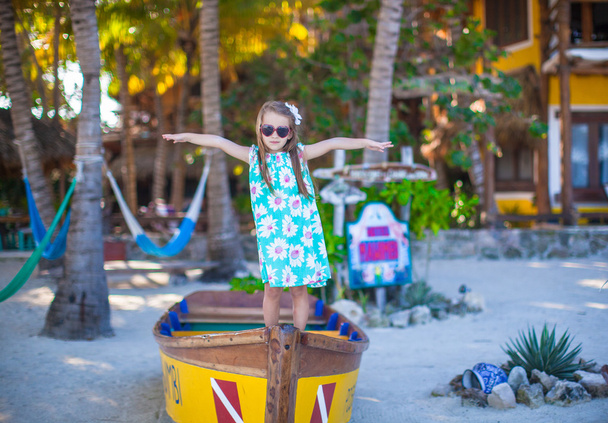 Маленька красива дівчинка в човні на пляжі на екзотичному курорті
 - Фото, зображення