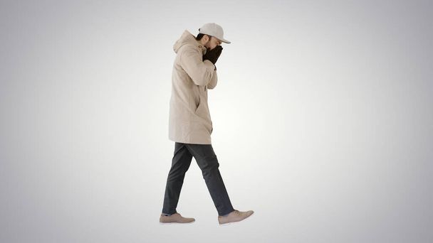 Caucasian man in a hat and coat coughing walking on gradient background. - Photo, Image