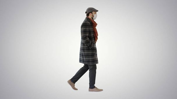 Gentleman wearing a protective face mask walking on gradient background. - Valokuva, kuva